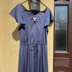 Mörkblå balklänning från H&M - Säljer en elegant mörkblå balklänning från H&M med v-ringning och korta volangärmar. Klänningen har knytband i midjan för en snygg passform och är tillverkad i ett mjukt, lätt material.