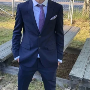 Mörkblå kostym från Dressmann slim fit - Säljer en stilren mörkblå kostym från Dressmann i slim fit-modell. Kavajen har två knappar, klassiska fickor och matchande byxor. Perfekt för bal eller student. Säljes för att jag har växt ur den annars är den bara använd en gång. Hela settet följer med skjorta, kostymen, slipsen och servetten (exkluderat skorna). 