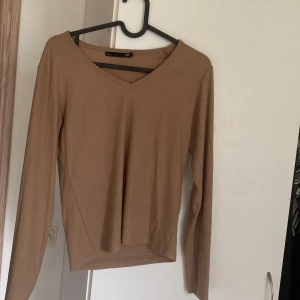 Ljus brun  ribbad långärmad tröja från 157 - Säljer en beige ribbad långärmad tröja från 157 med v-ringad hals. Färgen är finare brun i verkligheten 
