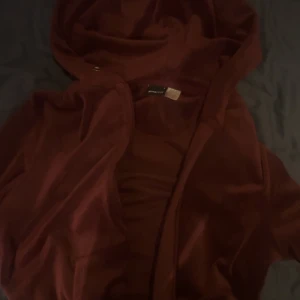 Vinröd hoodie från Gina Tricot - Säljer en vinröd hoodie från Gina Tricot i storlek S. Jackan har dragkedja framtill, huva och är långärmad. Perfekt för en avslappnad stil och enkel att matcha med olika outfits.