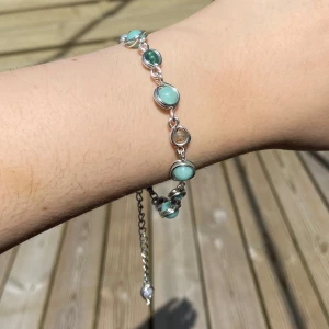 Silverarmband med turkosa stenar - Snyggt armband i silverfärg med runda turkosa och gröna stenar. Länkarna är tunna och armbandet har justerbar kedja med lås. Stenarna är infattade i silver och ger en fräsch och somrig vibe. Perfekt accessoar för att lyfta din stil.
