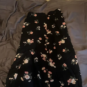 Blommig långkjol från Hollister - Supersöt svart långkjol från Hollister med blommigt mönster i rosa, vitt och beige. Kjolen har slits! Kolla bio! 💕