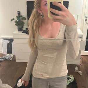 Beige ribbad långärmad topp H&M XS - Superenkel och snygg beige ribbad långärmad topp från H&M Basics. Modellen är figurnära med rundad, lite djupare urringning. Perfekt att styla med jeans eller kjol för en clean look. Mjuk och stretchig bomullsblandning.
