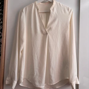 Vit/Cremevit Blus Åhléns - Vit/Cremevit blus från Åhléns använd ett fåtal gånger men inga defekter alls. Står ingen storlek men skulle nog säg att den är antingen S eller M. Extra knapp kommer med ifall den behövs! Nypris: Ca.499kr Axelbredd: 43cm Längd:57-58cm🤗