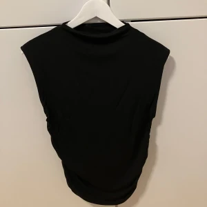 Svart topp - En svart, ärmlös topp från Gina Tricot i storlek M. 