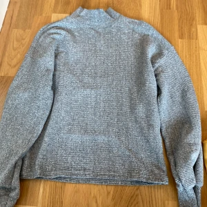 Grå ribbad polotröja - Säljer en grå ribbad polotröja med hög hals och lång ärm. Tröjan har en enkel och stilren look med diskreta ränder i materialet. Perfekt för lager-på-lager och passar till både jeans och kjol. I Kan mötas upp i Alingsås eller Trollhättan. Kan skickas men då tillkommer fraktkostnad.