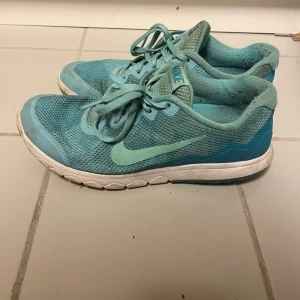 Turkosa Nike sneakers i mesh, strl 40 - Snygga turkosa Nike sneakers i meshmaterial med klassisk swoosh-logga på sidan. Skorna har snörning och vit sula med lätt struktur. Perfekta för dig som gillar sportig stil och vill ha lätta skor till träning eller vardag.