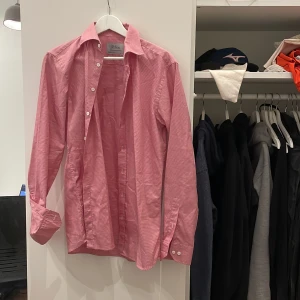 Rutig röd skjorta från Oscar Jacobson - Snygg rutig skjorta från Oscar Jacobson i röd och vitt. Skjortan har klassisk krage, vita knappar och är tillverkad i bomullstyg från Thomas Mason. Perfekt för dig som gillar stilrena detaljer och premiumkänsla.