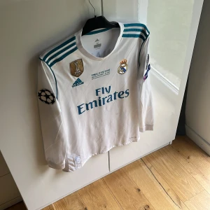 Real Madrid Ronaldo 7 Finaltröja Adidas - Säljer en officiell Real Madrid långärmad matchtröja från Champions League-finalen 2018 i Kiev. , Adidas-logga, klubbmärke, FIFA-märke och tryckta sponsorer. På ryggen står Ronaldo 7! Varan är lite smutsig!(inga defekter!) se sista bild! Autentisk!!!! Mvh ItsForfits🌟