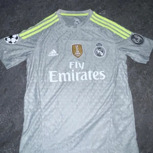 Real Madrid Ronaldo 7 bortatröja - Snygg grå Real Madrid bortatröja från Adidas med Ronaldo 7 på ryggen. Perfekt för fans av Ronaldo och Real.