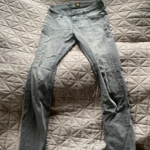 Grå skinny jeans från Lee - Säljer ett par gråa skinny jeans från Lee med klassisk femficksdesign och Lee-logga på bakfickan. Jeansen har smal passform och är tillverkade i mjukt denimtyg. Perfekta för dig som gillar en clean och stilren look.