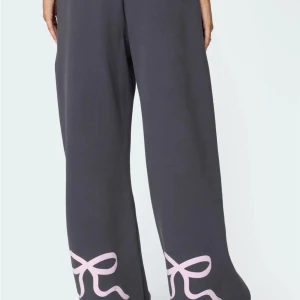 Mörkgrå mjukisbyxor med rosa rosett-detaljer - Säljer mina högt egons mjukisbyxor ifrån usa! De kostade 72 dollar och ca 700 kr. De har lite noppror på framsidan och lite på insidan. De är Mörkgrå mjukisbyxor med vida ben och stora ljusrosa rosetter tryckta längst ner på båda benen. ❤️❤️❤️