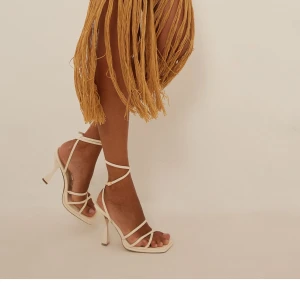 Beige Klackar från NA-KD - Snygga beige klackar från NA-KD med flera tunna remmar och fyrkantig tå. Perfekta för en stilren look.