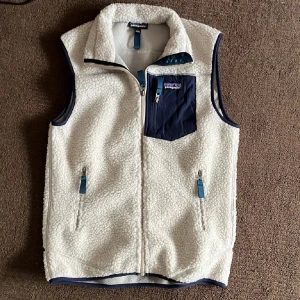  Fleeceväst från Patagonia - Säljer en snygg vit fleeceväst frán Patagonia storlek M. Toppskick helt ny använd den bara få gånger! Perfekt för lager-pä-lager under kyliga dagar. Tveka inte vid funderingar!