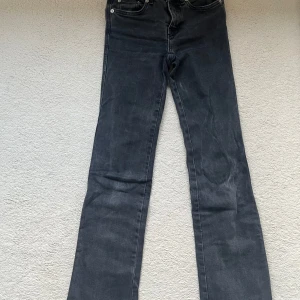 Svarta bootcut jeans från 157 - Säljer ett par svarta bootcut jeans från 157 med klassisk femficksdesign och snygga detaljer på bakfickan. Jeansen har en 90-talsinspirerad passform och är perfekta för dig som gillar retrostil.