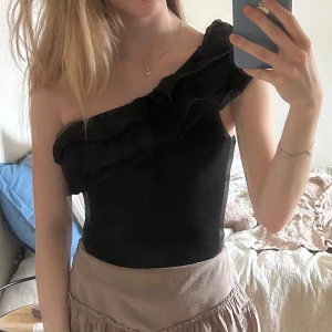 Svart oneshoulder body med volang strl S 70kr - Säljer en svart oneshoulder topp med volangdetalj över axeln. Det är en body. Strl S, superfin!! knappt använd 70kr Zara