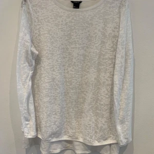 Vit långärmad topp från Lindex - Säljer en vit långärmad topp från Lindex med diskret leopardmönster. Tunt och lätt material som passar perfekt till lager-på-lager. Rund halsringning och normal passform.