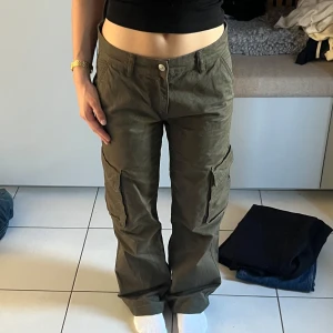 Olivgröna cargopants med raka ben - Säljer ett par olivgröna cargopants med raka ben och flera fickor på sidorna. Byxorna har normal passform och stängs med knapp och dragkedja. Perfekta för en avslappnad och trendig stil.
