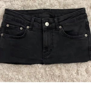 Svart jeanskjol - ⚠️PRIS GÅR ATT DISKUTERA⚠️ Supersnygg svart jeanskjol i mini-längd. Klassisk femficksdesign med knapp och dragkedja fram Bakfickor med lock och silverknapp för en unik look Rå kant nertill för en trendig, avslappnad stil Väldigt lite använd – i mycket fint skick Passar perfekt till både vardags- och festoutfits!
