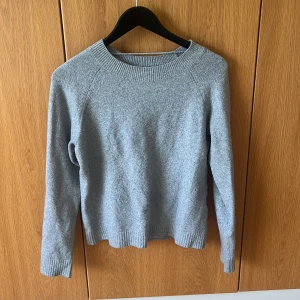 Ljusgrå stickad tröja från vero moda - En enkel och stilren ljusgrå stickad tröja med rund halsringning och långa ärmar. Tröjan har ribbade muddar vid ärmslut, hals och nederkant. från vero moda