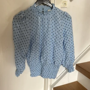 Neo noir blus - Blus med volang nertill och knäppning i nacken 