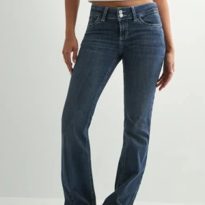 Nelly jeans - Snygga blå jeans med bootcut passform och klassisk femficksdesign. Jeansen har broderade detaljer på bakfickorna och stängs med dragkedja och två knappar framtill. Perfekta för en avslappnad men trendig look.