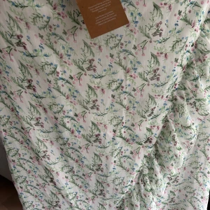 Blommig kjolfrån Vero Moda - Söt kjol från Vero Moda med blommigt mönster i grönt, rosa och blått på vit botten. Klänningen har resår i midjan och är perfekt för vår och sommar. Lätt och luftig modell som passar till många tillfällen.