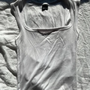 Vit linnetopp från Gina Tricot - Klassisk vit linnetopp från Gina Tricot med breda axelband och rundad halsringning. Perfekt att styla till jeans eller kjol för en enkel och fräsch look. Man får gärna be om fler bilder!💞