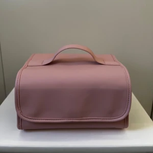 Rosa necessär med flera fack - Praktisk rosa necessär med handtag från H&M och flera genomskinliga fack med dragkedja. Perfekt för att organisera smink, hudvård eller andra småsaker. Väskan kan rullas ihop och är lätt att ta med på resan. Plastet ser ut som om den har vita fläckar men det är inte smutsigt utan den blev så av sig själv. Priset kan diskuteras. 