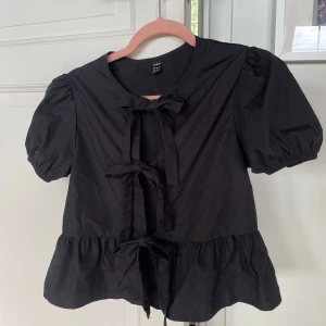 Svart blus med rosetter - Råka beställa två därför säljer jag. Sitter super snyggt! 🖤