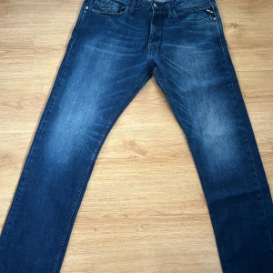 Mörkblå Replay jeansbyxor straight fit - Säljer ett par mörkblå jeans från Replay med klassisk femficksdesign och raka ben. Jeansen har snygga slitningar och silverfärgade detaljer vid fickorna. Perfekta för dig som gillar en tidlös och avslappnad stil. W34 L32. Pris ej hugget i sten.