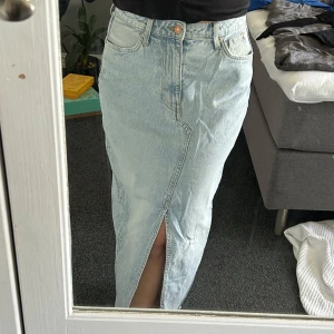 Ljusblå jeanskjol med slits - Säljer en lång ljusblå jeanskjol med hög midja och snygg slits framtill. Helt oanvänd och i nyskick!