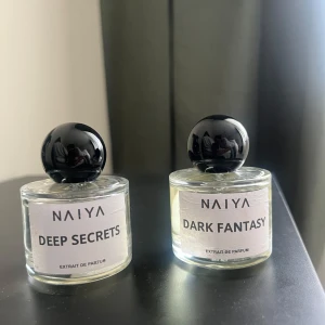 Parfymset från Naiya – Deep Secrets & Dark Fantasy - Säljer båda för 200 kr! Två exklusiva parfymer från Naiya: Deep Secrets och Dark Fantasy. Båda kommer i runda, genomskinliga glasflaskor med svart, klotformad kork och stilren vit etikett. Extrait de Parfum för en intensiv doftupplevelse.   