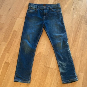 Slim fit lee jeans - Säljer ett par klassiska blå jeans från Lee i modellen slim fit. Jeansen har fem fickor, slim passform och är tillverkade i bomull. Perfekta för dig som gillar en tidlös stil och vill ha ett par slitstarka jeans.