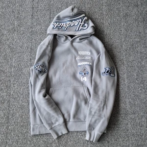 Grå mjukisbyxor och hoodie från Hoodrich - Grå/blå mjukisbyxor från Hoodrich med broderad logga framtill och liten brodyr bak. Byxorna har normal passform, resår i midjan och sidofickor. Sedan en grå/blå hoodie från hoodrich med broderad logga fram- och baktill med en ficka i vänstra armen. Storlek M på hoodien och L på byxorna.