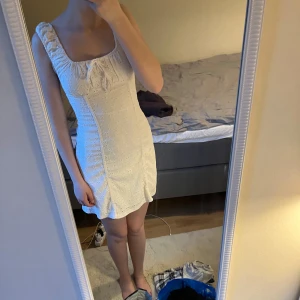 Super bekväm vit klänning - Supersöt vit kortklänning med breda axelband, volangdetaljer och broderat hålmönster. Klänningen har en söt knytning framtill och silkes material innanför. Själv älskar jag klänningen men säljes pga att den är för liten🙂