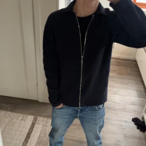 Marinblå tröja ifrån Åhléns/SANDÖ - Snygg marinblå zip tröja  från Åhléns/SANDÖ med dragkedja framtill. Perfekt för en stilren look. Passar bra till jeans eller chinos.     Använd 1-2 gånger.