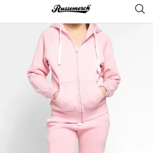 Rosa hoodie från Russemmerch - Säljer en mysig rosa hoodie från Russemmerch med dragkedja och justerbar huva. Tröjan har långa ärmar och en bekväm passform med fickor framtill. Perfekt för en avslappnad stil.🩷🩷 Den har en liten defkekt på armbågen som säkert går att tvätta bort, syns knappt. Hör av er om ni vill se💕Köpt för 750