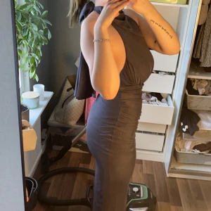 Grå långklänning - Snygg grå långklänning med halterneck-design. Klänningen har en tight passform som framhäver figuren och är perfekt för en elegant look. Klänningen är testad och prislapp sitter kvar, perfekt till bal💃