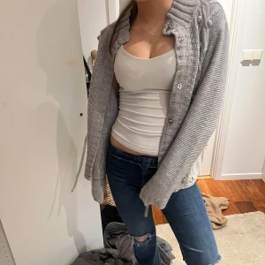 2000s Grå kofta med knappar -  Säljer en mysig grå kofta med knappar och ribbad krage. Perfekt för kyliga dagar och lätt att matcha med olika outfits.