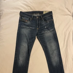 Diesel Jeans  - Snygga blå jeansbyxor från Diesel med en slim passform. De har en klassisk femficksdesign och en diskret slitning för en trendig look. Perfekta för en stilren vardagsoutfit. Skönt och stretchigt tyg. 