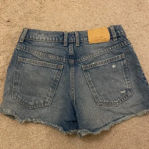 Blå jeansshorts från Zara - Säljer ett par fina blå jeansshorts från Zara med slitna detaljer och fransar. Inte använda mycket ❤️