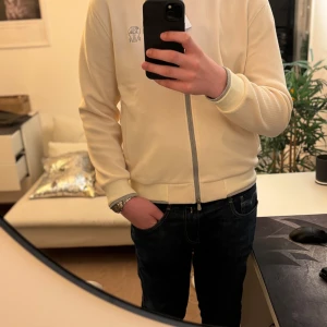 Brunello Cucinelli kofta - Säljer en stilren beige kofta från Brunello Cucinelli. Kofta har en dragkedja framtill och är långärmad med ribbade muddar. Den är broderad med en diskret logotyp på bröstet. Perfekt för en elegant och avslappnad look. Nypris ligger på typ 14 tusen och den är köpt i Italien i en av deras butiker. Den säljs på grund av att jag inte använder den och har använt den typ 5 gångar bara.