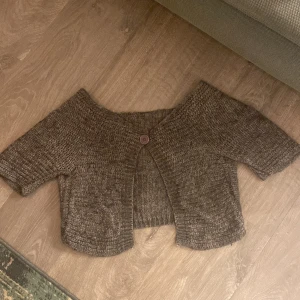 Brun stickad kofta med knapp - Säljer en mysig brun stickad kofta med korta ärmar och en knapp framtill. Koftan har en croppad passform. köpt på plick