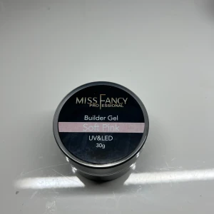Builder Gel Soft Pink från Miss Fancy - Builder Gel i färgen Soft Pink från Miss Fancy, perfekt för att skapa hållbara och snygga naglar. Gelen är kompatibel med både UV och LED-lampor och kommer i en burk om 30g. Den mjuka rosa nyansen ger en naturlig och elegant look.