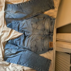 Blå jeans från Replay - Snygga blå jeans från Replay med klassisk femficksdesign och en liten metall-logga vid fickan. De har en normal passform och är tillverkade i slitstarkt denim. Perfekta för en avslappnad stil.              Använda storlek 166