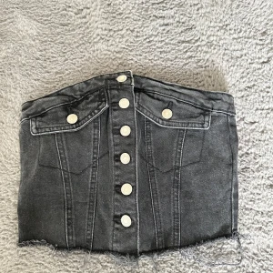 Svart jeanskorsett med knappar - Snygg svart jeanskorsett med knappar i storlek XS men skulle säga att den passar xxs bättre. Använd fåtal gånger.