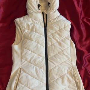 Vit Zara väst - Snygg vit quiltad dunväst med dragkedja och huva. Perfekt för kyligare dagar och ger en stilren look. Västen har en normal passform och är lätt att matcha med olika outfits. Tvättas självklart innan den postas❤️