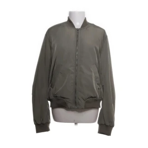 Olivgrön bomberjacka från H&M - Snygg olivgrön bomberjacka från H&M. Jackan har en klassisk bomberstil med en orange insida. 