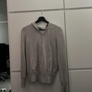 Grå hoodie från Soft Goat, 100% Kashmir  - Säljer en stilren grå hoodie från Soft Goat i 100% kashmir. Tröjan har dragkedja framtill och en mysig huva. 